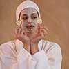 Spa Woman applying Facial Mask  Beauty Treatments  Close up portrait of beautiful girl with a towel on her head applying facial mask