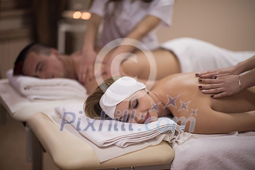 Relaxed young beautiful couple receiving a back massage from masseur in a spa Relaxed young beautiful couple receiving a back massage from masseur in a spa