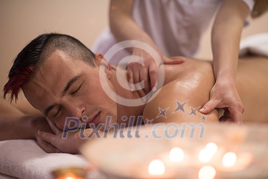 Positive young man having a back massage in a spa center Positive young man having a back massage in a spa center