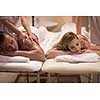 Relaxed young beautiful couple receiving a back massage from masseur in a spa