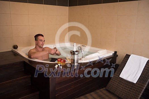 young handsome man enjoys relaxing in the jacuzzi with candles and champagne at luxury resort spa young handsome man enjoys relaxing in the jacuzzi with candles and champagne at luxury resort spa
