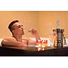 young handsome man enjoys relaxing in the jacuzzi with candles and champagne at luxury resort spa