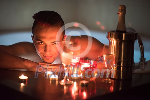 young handsome man enjoys relaxing in the jacuzzi with candles and champagne at luxury resort spa young handsome man enjoys relaxing in the jacuzzi with candles and champagne at luxury resort spa