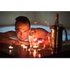 young handsome man enjoys relaxing in the jacuzzi with candles and champagne at luxury resort spa