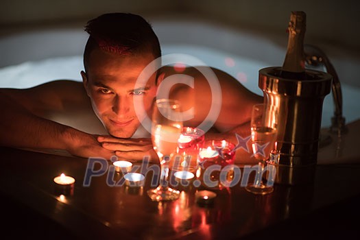 young handsome man enjoys relaxing in the jacuzzi with candles and champagne at luxury resort spa young handsome man enjoys relaxing in the jacuzzi with candles and champagne at luxury resort spa