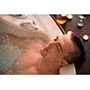 young handsome man enjoys relaxing in the jacuzzi with candles and champagne at luxury resort spa