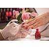 Woman hands receiving a manicure in beauty salon. Nail filing. Close up, selective focus.