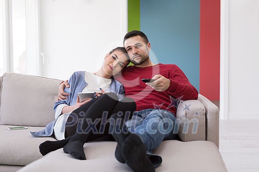 Young couple on the sofa watching television together in their luxury home Young couple on the sofa watching television together in their luxury home