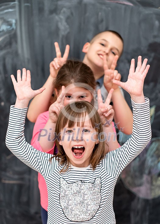 group portrait of happy childrens standing one behind the other while having fun in front of black chalkboard group portrait of happy childrens standing one behind the other while having fun in front of black chalkboard