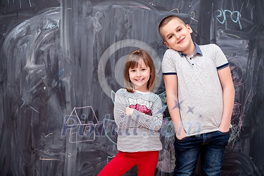 group portrait of happy childrens boy and little girl standing in front of black chalkboard group portrait of happy childrens boy and little girl standing in front of black chalkboard