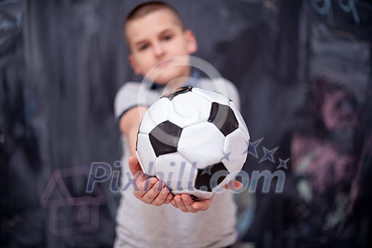 portrait of happy cute boy having fun holding a soccer ball while standing in front of black chalkboard portrait of happy cute boy having fun holding a soccer ball while standing in front of black chalkboard