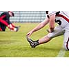 group of young american football players warming up and stretching together before a practice on the field