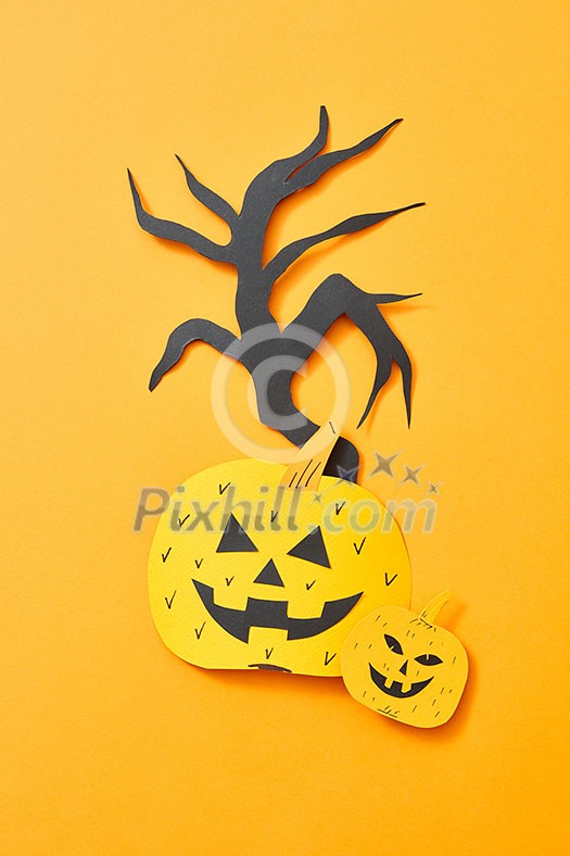 Handcraft paper tree and scary pumpkins on an orange background with space for text. Creative layout for Halloween. Flat lay Handcraft paper tree and scary pumpkins on an orange background with space for text. Creative layout for Halloween. Flat lay