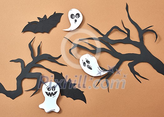 Creative composition of paper with flying bats and ghosts over tree branches on a brown background with space for text. Handcraft layout for Halloween. Flat lay Creative composition of paper with flying bats and ghosts over tree branches on a brown background with space for text. Handcraft layout for Halloween. Flat lay