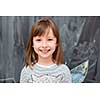 portrait of  happy smiling cute little girl standing in front of black chalkboard