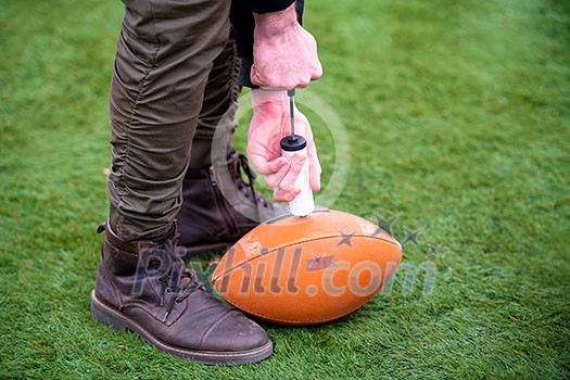 close up shot of man on the field pumping air into a professional ball for american football close up shot of man on the field pumping air into a professional ball for american football
