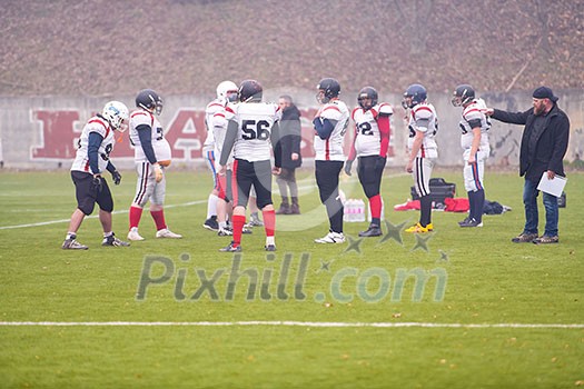 group of young professional american football players with coach discussing strategy together during training match on the stadium field group of young professional american football players with coach discussing strategy together during training match on the stadium field