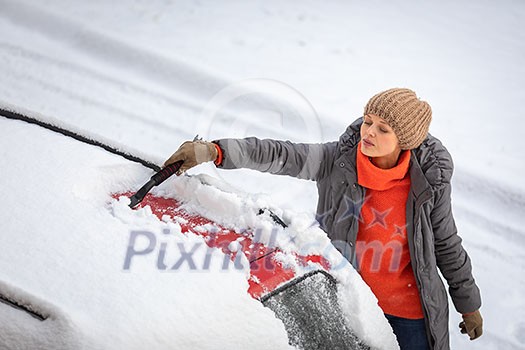 Pretty, young woman cleaning her car from snow after heavy snowstorm (color toned image) Pretty, young woman cleaning her car from snow after heavy snowstorm (color toned image)
