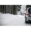 Car on a snowy winter road amid forests - using its four wheel drive capacities to get through the snow