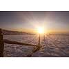 Beautiful winter landscape during sunset over snow covered field