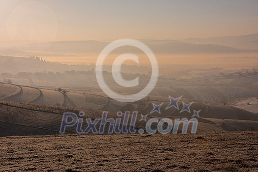 Beautiful winter landscape during sunset over snow covered field with fog and pollution in the valley behind Beautiful winter landscape during sunset over snow covered field with fog and pollution in the valley behind