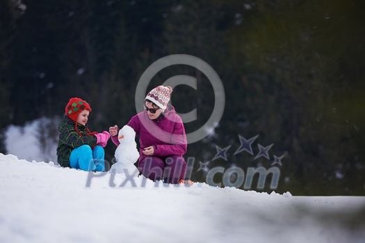 happy young family playing in fresh snow and building snowman at beautiful sunny winter day outdoor in nature happy young family playing in fresh snow and building snowman at beautiful sunny winter day outdoor in nature