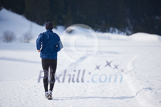 young man jogging on snow in forest, bautiful sunny winter day. handsome sporty ahtlete man running young man jogging on snow in forest, bautiful sunny winter day. handsome sporty ahtlete man running