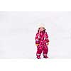 happy cute little girl wearing a red snow suit and white hat  while having fun and playing on fresh snow at snowy winter day