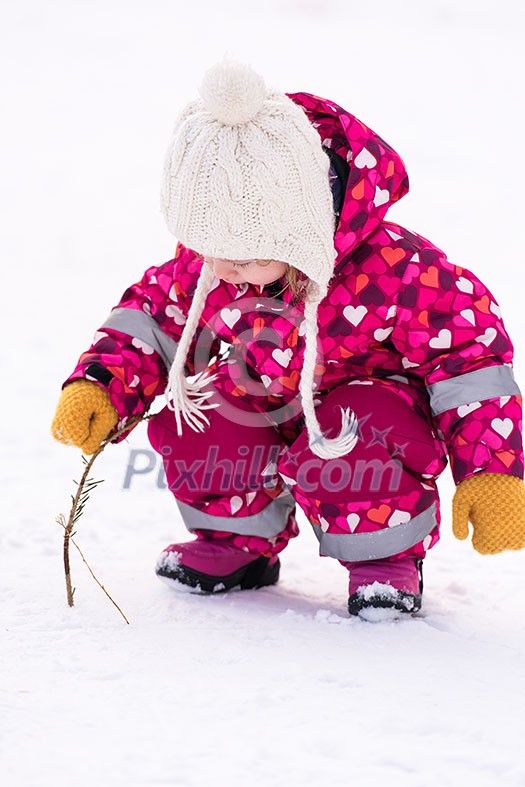 happy cute little girl wearing a red snow suit and white hat while having fun and playing on fresh snow at snowy winter day happy cute little girl wearing a red snow suit and white hat while having fun and playing on fresh snow at snowy winter day