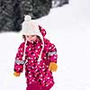 happy cute little girl wearing a red snow suit and white hat  while having fun and playing on fresh snow at snowy winter day