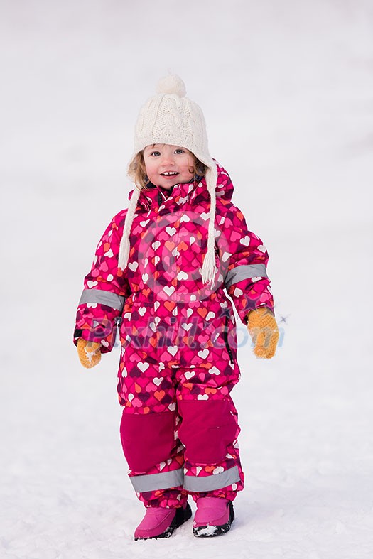 happy cute little girl wearing a red snow suit and white hat while having fun and playing on fresh snow at snowy winter day happy cute little girl wearing a red snow suit and white hat while having fun and playing on fresh snow at snowy winter day