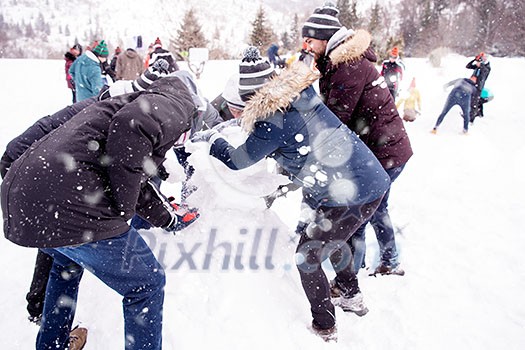 group of young happy business people having a competition in making snowmen while enjoying snowy winter day with snowflakes around them during a team building in the mountain forest group of young happy business people having a competition in making snowmen while enjoying snowy winter day with snowflakes around them during a team building in the mountain forest