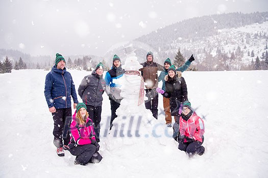 group portrait of young happy business people after a competition posing with finished snowman while enjoying snowy winter day with snowflakes around them during a team building in the mountain forest group portrait of young happy business people after a competition posing with finished snowman while enjoying snowy winter day with snowflakes around them during a team building in the mountain forest