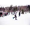 group of young happy business people having a running competition using snowshoes while enjoying snowy winter day with snowflakes around them during a team building in the mountain forest