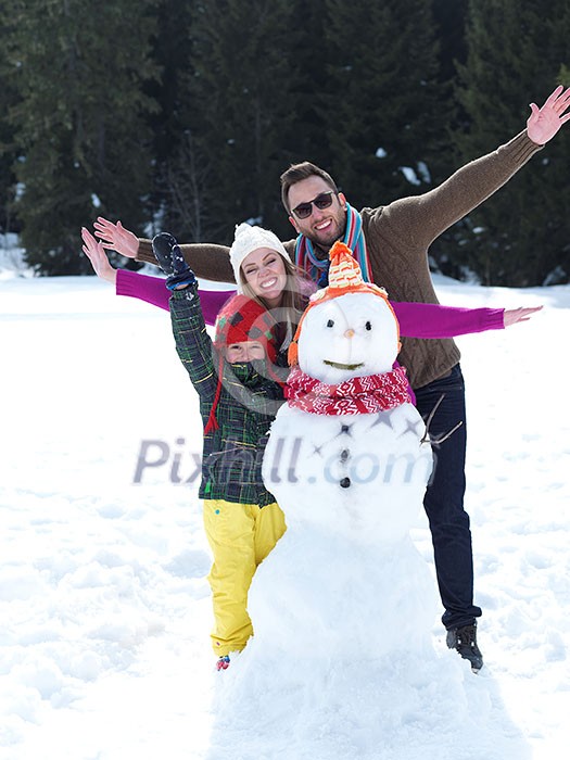 happy young family playing in fresh snow and making snowman at beautiful sunny winter day outdoor in nature with forest in background happy young family playing in fresh snow and making snowman at beautiful sunny winter day outdoor in nature with forest in background