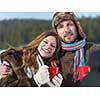 portrait of happy young couple outdoor on winter day drinking warm tea with fresh snow in background