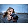 Pretty, young woman taking photos with her professional dslr camera