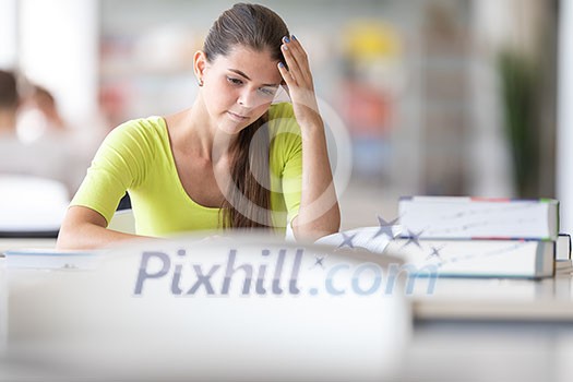 Stressed and fully concentrated female university/highschool student with books in library Stressed and fully concentrated female university/highschool student with books in library