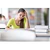 Stressed and fully concentrated female university/highschool student with books in library