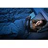 Pretty, middle-aged woman using her tablet computer before sleep in bed in the evening