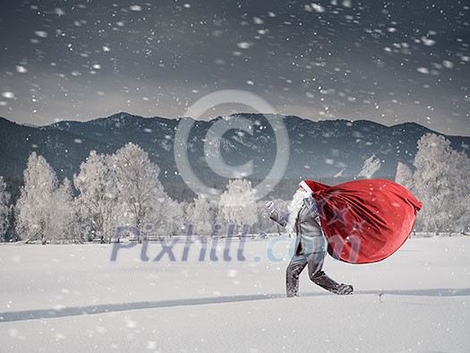 Businessman in Santa hat running with big red bag on back. Mixed media Businessman in Santa hat running with big red bag on back. Mixed media