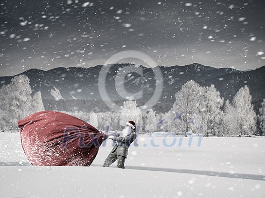 Santa Claus among snow pulling big gift bag Santa Claus among snow pulling big gift bag