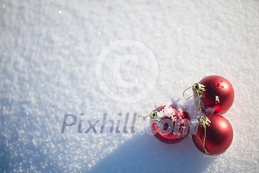 christmas red balls with long shadows in fresh snow on beautiful sunny winter day christmas red balls with long shadows in fresh snow on beautiful sunny winter day