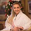 people, and relaxation concept   beautiful young woman in bath robe drinking champagne at spa over holidays lights background