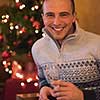 Portrait of a happy young man with a glass of champagne celebrating winter holidays at home beautifully decorated for Christmas