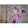 young happy casual business woman wearing a red hat and blowing party whistle while having new years confetti party in front of concrete wall