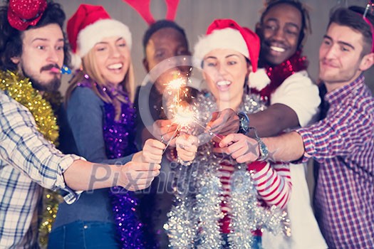 multiethnic group of young happy casual business people lighting a sparkler and having fun while celebrating new year eve in front of concrete wall at new startup office multiethnic group of young happy casual business people lighting a sparkler and having fun while celebrating new year eve in front of concrete wall at new startup office