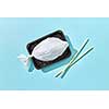 Dinner set of fish from plastic bag served wooden chopsticks with hard shadows on a pastel blue background, copy space. Ecological problem of ocean pollution.