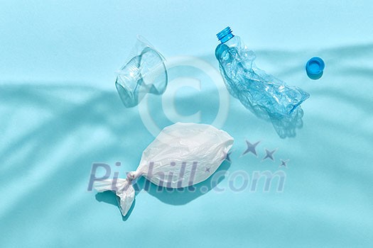 Fish in polythene bag and plastic bottles are floating under water from shadows on a pastel blue background, copy space. Ecological problem of pollution world ocean. Fish in polythene bag and plastic bottles are floating under water from shadows on a pastel blue background, copy space. Ecological problem of pollution world ocean.