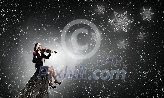 Woman in formal suit and Santa hat playing violin Woman in formal suit and Santa hat playing violin